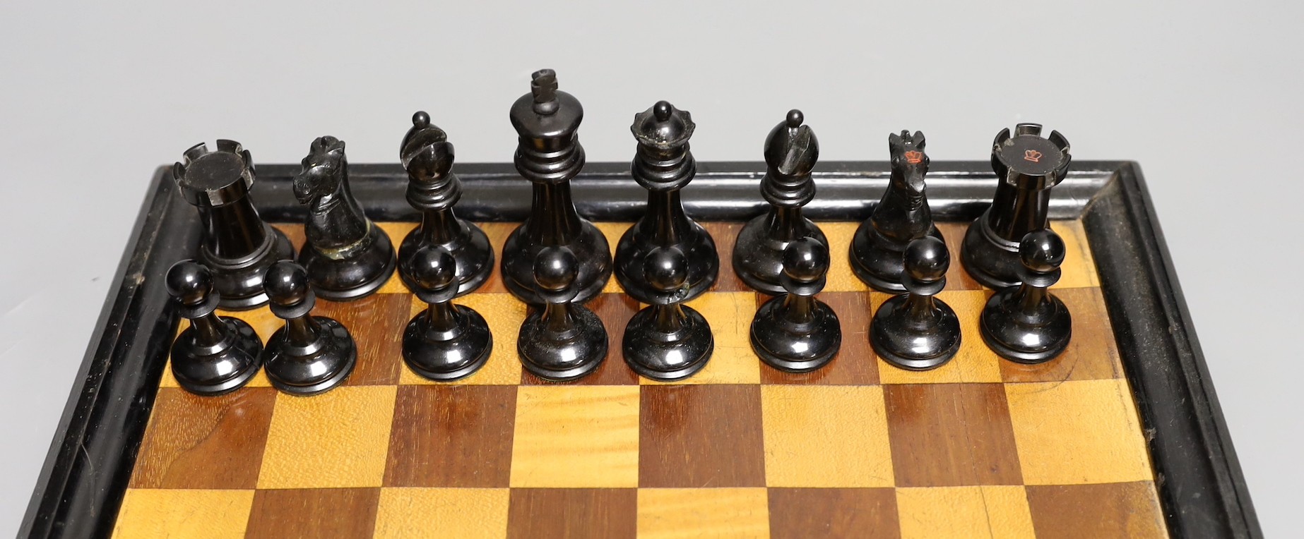 A late 19th / early 20th century weighted Staunton chess set, red crown stamps, kings 7.5cm, with inlaid chess board 32cm